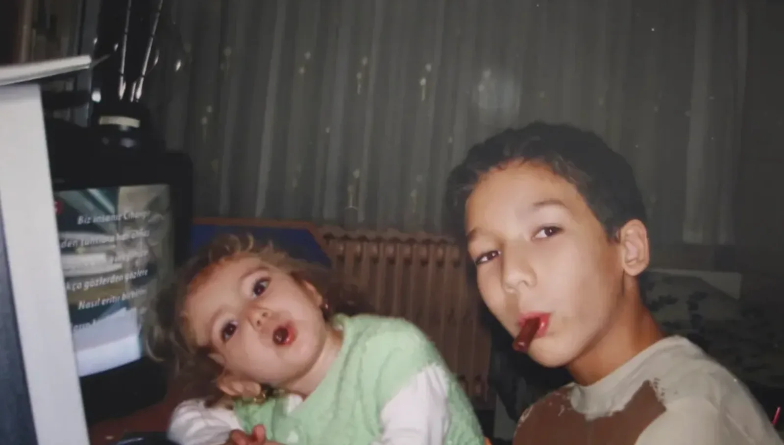 Efe as a child sitting at a computer with his younger sibling.